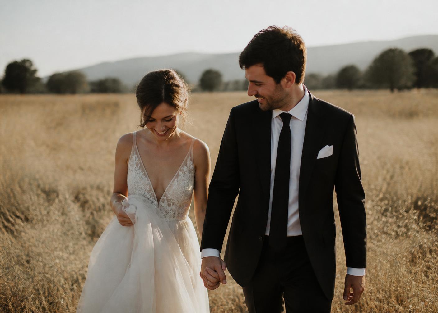 Bride and groom walking through a golden field at sunset